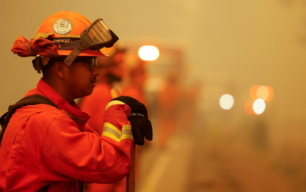 A member of the California Department of Corrections and Rehabilitation Vallecito Fire Crew watch a section of road for spot fires to slow the spread of the Dixie Fire, a wildfire near the town of Westwood, California, U.S. August 8, 2021. REUTERS/Fred Gr