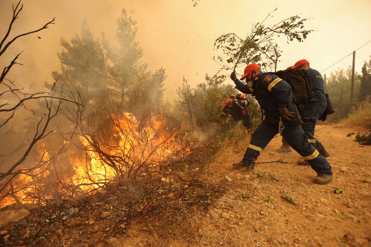 Firefighters and volunteers try to extinguish a wildfire burning in the village of Galatsona, on the island of Evia, Greece, August 9, 2021. REUTERS/Nicolas Economou
