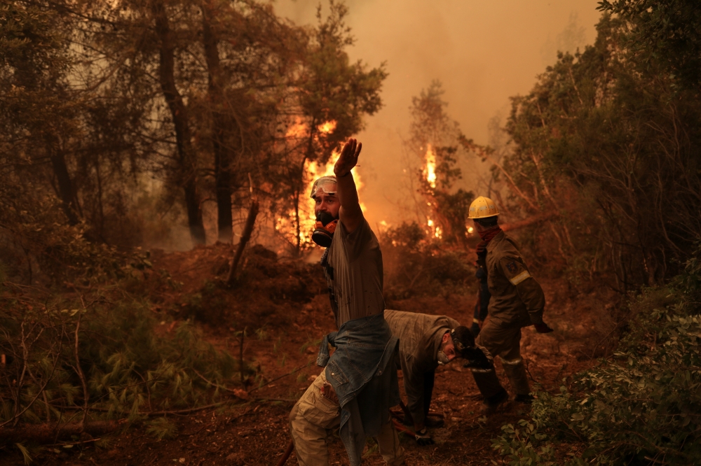 A volunteer reacts as a wildfire burns in the village of Galatsona, on the island of Evia, Greece, August 9, 2021. REUTERS/Stelios Misinas