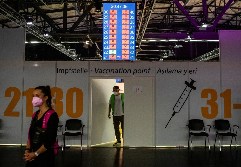 A worker peers out of a door in front of COVID-19 vaccination booths at the Arena Treptow vaccination centre in Berlin, Germany, August 9, 2021. John Macdougall/Pool via Reuters 