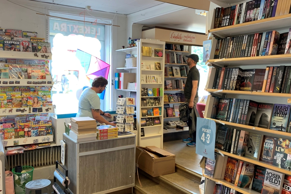 A man looks at items as a staff member works at a local bookstore in east-coast small-town Trosa, Sweden August 11, 2021. REUTERS/Anna Ringstrom
