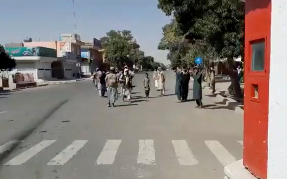 People gather on the street as Taliban fighters stand guard on main road intersection in city of Ghazni, Afghanistan in this screen grab taken from a video released by the Taliban on August 12, 2021. Taliban Handout/via Reuters 