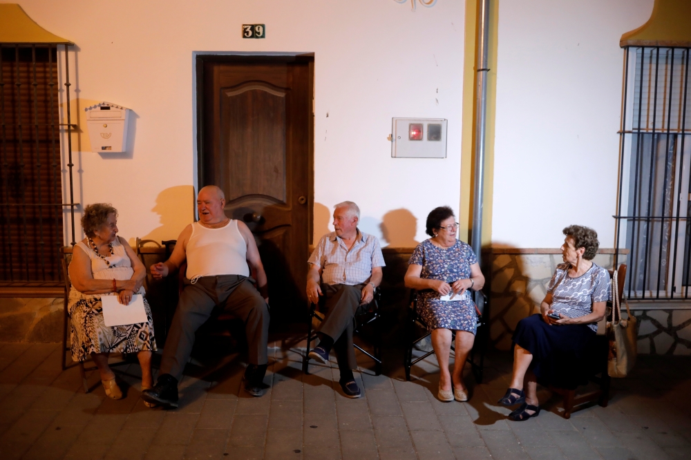 Neighbours chat outside their houses to avoid the heat at night, as a heatwave hits Spain, in Algar, August 12, 2021. Picture taken August 12, 2021. REUTERS/Jon Nazca