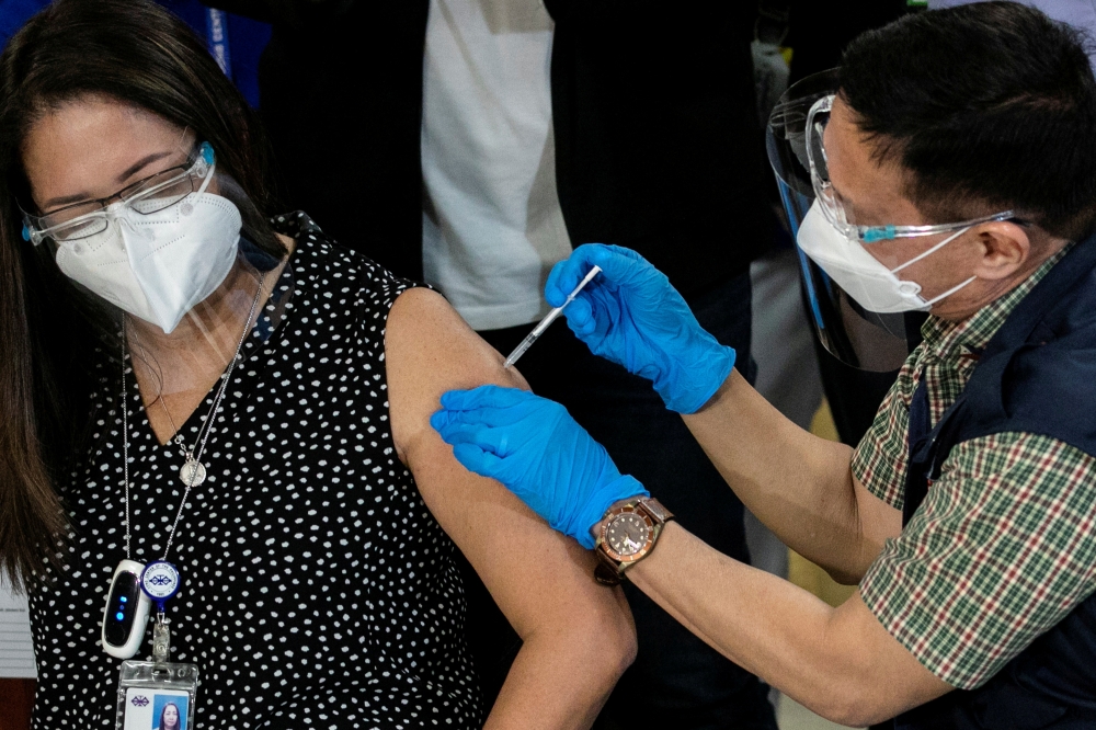 File photo: Philippines' Health Secretary Francisco Duque vaccinates a health worker with Sinovac Biotech's Coronavac on the first day of the coronavirus disease (COVID-19) inoculation drive in the Philippines, at the Lung Center of the Philippines, Quezo