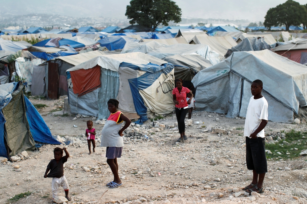 FILE PHOTO: Haitians made homeless in the 2010 earthquake stand outside their tents on the outskirts of Port-au-Prince January 13, 2011. REUTERS/Jorge Silva
