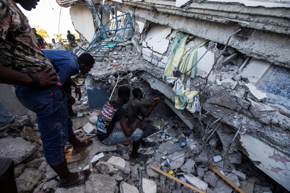 People look for survivors at a house destroyed following a 7.2 magnitude earthquake in Les Cayes, Haiti August 14, 2021. REUTERS/Ralph Tedy Erol 