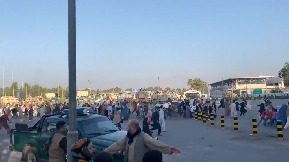 A horde of people run towards the Kabul Airport Terminal, after Taliban insurgents took control of the presidential palace in Kabul, August 16, 2021, in this still image taken from video obtained from social media. Jawad Sukhanyar/via Reuters