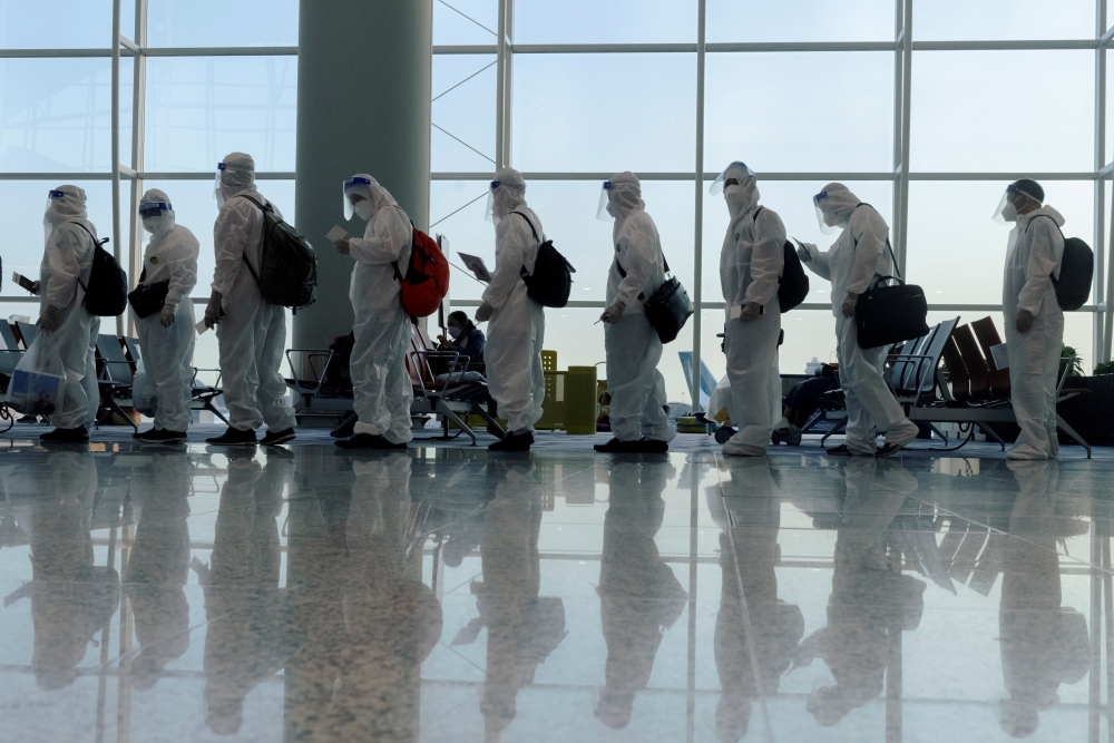 File photo: Passengers wearing protective suits (PPE) line up to board their plane for an international flight at Hong Kong airport amid the spread of the coronavirus disease (COVID-19), China July 9, 2021. Reuters/Thomas Peter/File Photo