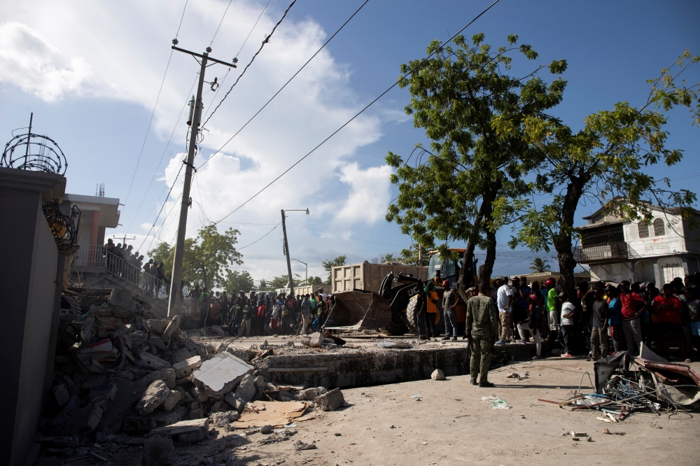 People look at a damaged house after a 7.2 magnitude earthquake in Les Cayes, Haiti August 15, 2021. REUTERS/Estailove St-Val