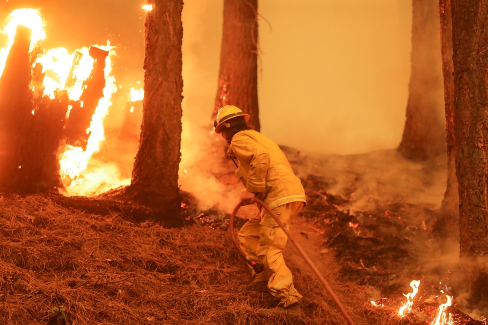 A firefighter continues to hold the line of the Dixie Fire near Taylorsville, California, U.S., August 10, 2021. REUTERS/David Swanson/File Photo