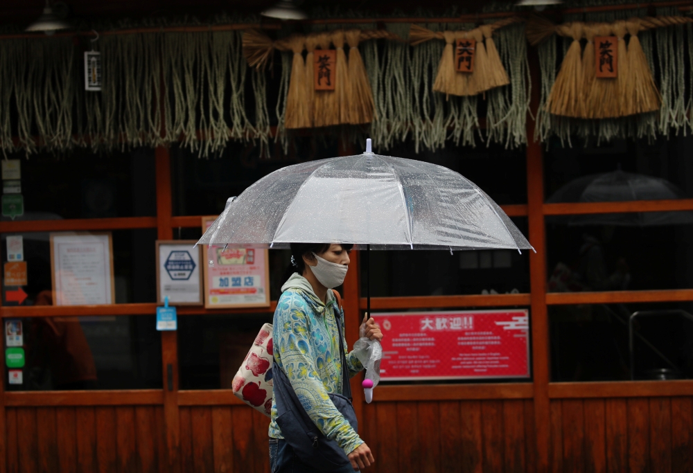 A woman wearing a protective mask, amid the coronavirus disease (COVID-19) outbreak, walks past a temporarily closed restaurant in Fukuoka, Fukuoka Prefecture, Japan, August 17, 2021. REUTERS/Kim Kyung-Hoon