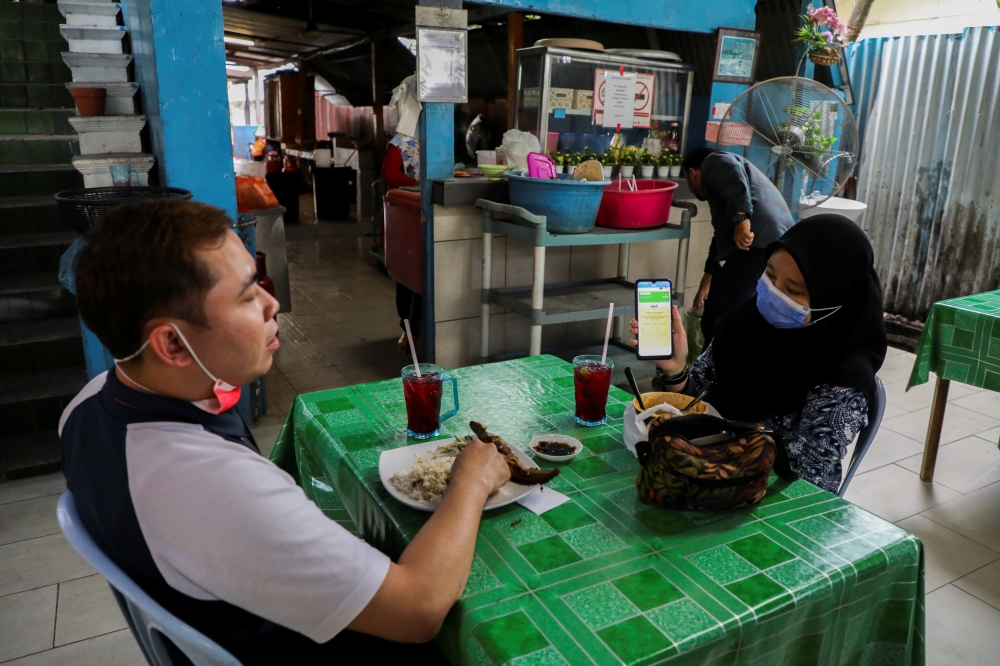 A diner shows her digital vaccination certificate at a restaurant, amid the coronavirus disease (COVID-19) outbreak in Kuala Lumpur, Malaysia August 20, 2021. REUTERS/Lim Huey Teng