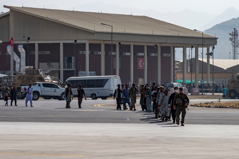 A U.S Marine leads evacuees to a U.S. Air Force C-17 Globemaster III aircraft, deployed with the 816th Expeditionary Airlift Squadron, in support of Operation Allies Refuge at Hamid Karzai International Airport in Kabul, Afghanistan, August 20, 2021.