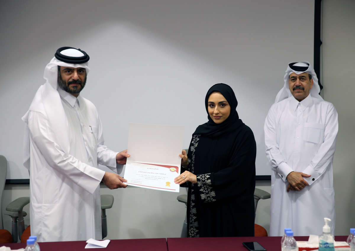 Assistant Undersecretary for Private Education Affairs at the Ministry of Education and Higher Education Omar Abdel Aziz Al Naama honouring a volunteer during a ceremony.