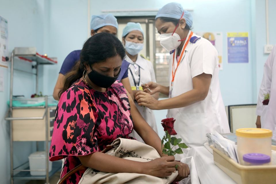A healthcare worker holding a rose is vaccinated against COVID-19 at a medical centre in Mumbai, India, January 16, 2021. REUTERS/Francis Mascarenhas/File Photo
