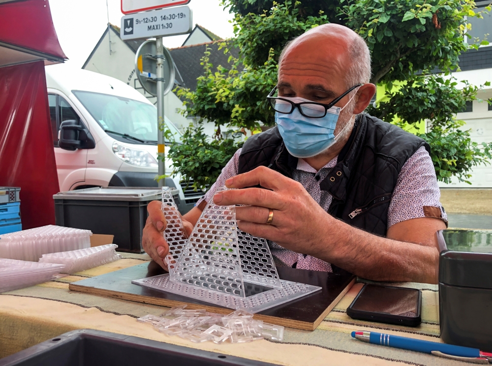 French beekeeper Denis Jaffre, inventor of a trap designed to catch Asian giant hornets, sits in a stall at a market in Pencran, France, August 18, 2021. Reuters/Manuel Ausloos