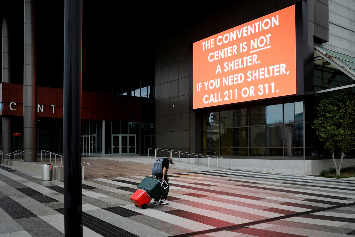 A man pulling a cart with his belongings walks past a billboard outside the Ernest N. Morial Convention Center ahead of Hurricane Ida, in New Orleans, Louisiana, U.S. August 29, 2021. REUTERS/Marco Bello
