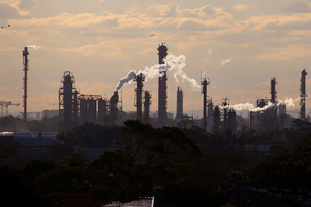 Birds and a plane are seen flying above emission from the chimneys of a chemical plant located near Port Botany in Sydney, Australia June 2, 2017. REUTERS/David Gray/File Photo