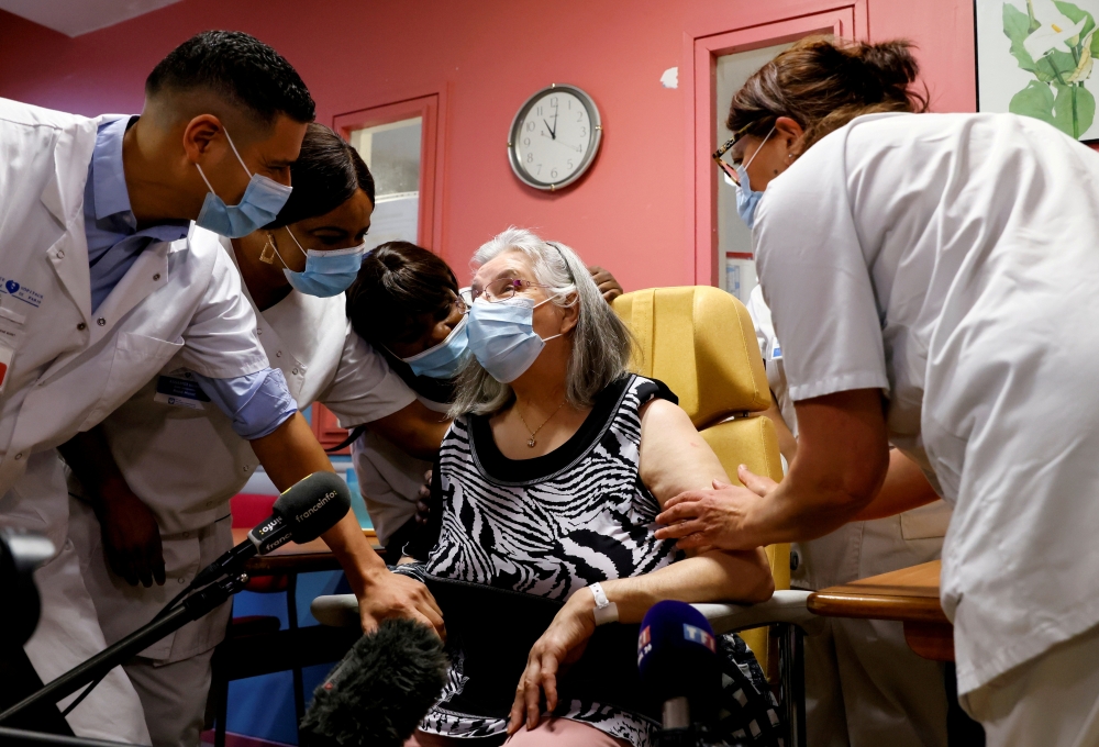 Health workers speak with Mauricette, a 78-year-old French woman, after she received the first dose of the Pfizer-BioNTech coronavirus disease (COVID-19) vaccine in the country, at the Rene-Muret hospital in Sevran, on the outskirts of Paris, France, Dece