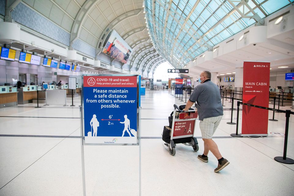 A man pushes a baggage cart wearing a mandatory face mask as a 