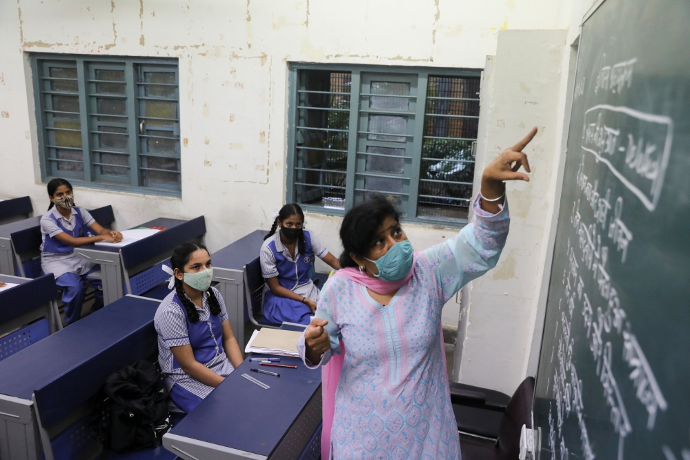 A teacher gives a lesson inside a classroom following the reopening of schools at 50% capacity for the students of classes 9 to 12 after months of closure due to the coronavirus disease (COVID-19) outbreak, at a government school in New Delhi, India, Sept