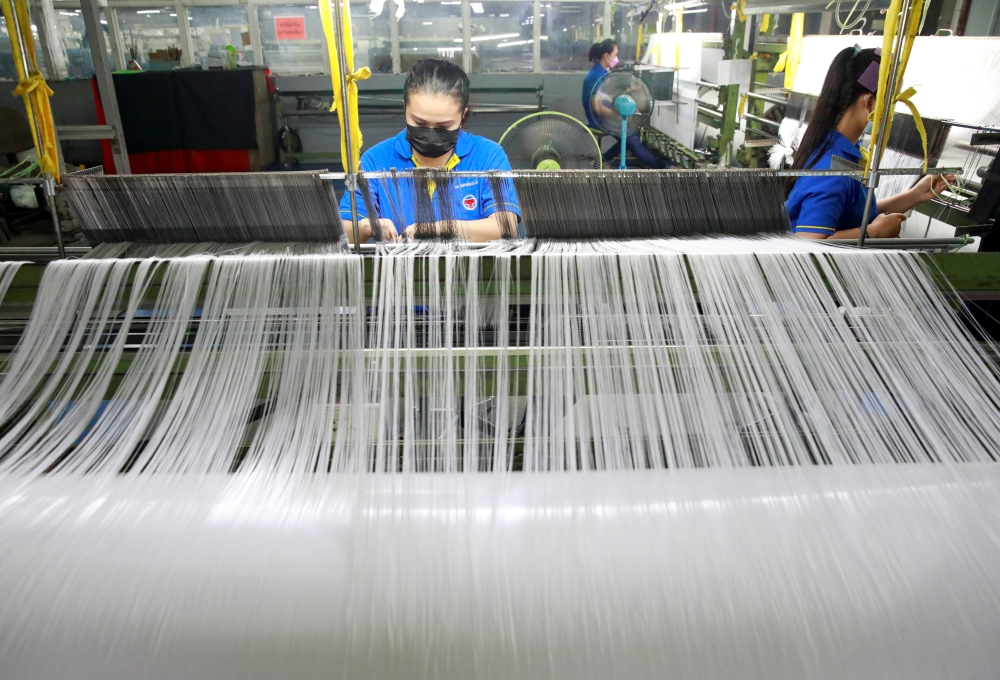 Women work in a weaving factory, as Bangkok city administration and temples drive efforts to encourage the public to donate plastic bottles, which will be collected and upcycled into reusable Personal Protective Equipment (PPE) to reduce plastic waste as 