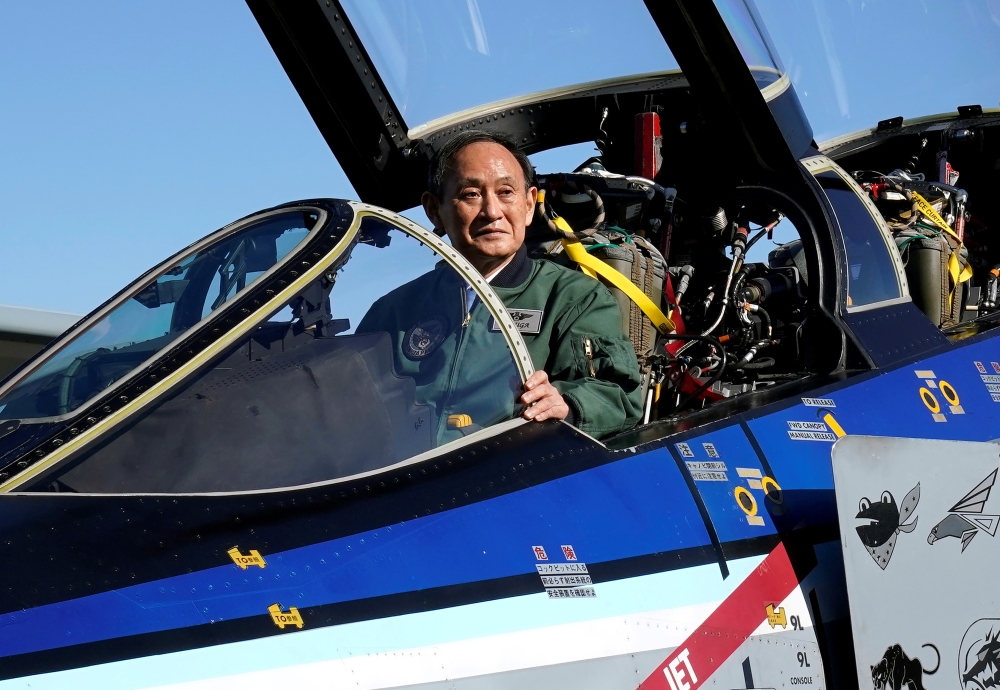 Japanese Prime Minister Yoshihide Suga sits in the cockpit of a F4EJ Kai jet fighter of Japan's Air Self-Defense Force at Iruma Air Base in Sayama, Saitama Prefecture, Japan, November 28, 2020. Kimimasa Mayama/Pool via REUTERS/File Photo