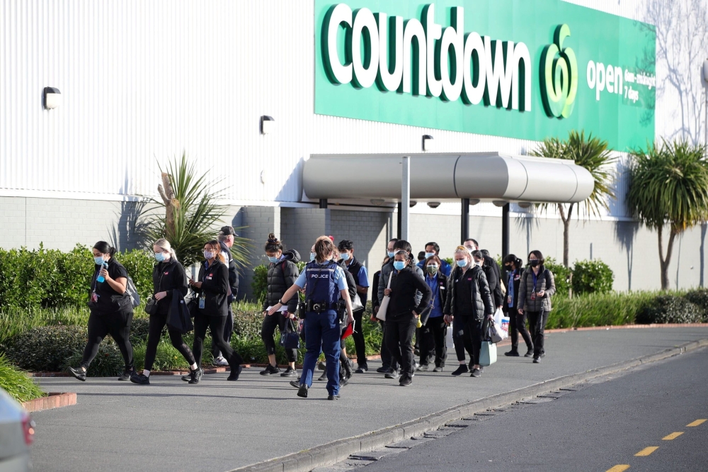 A police officer leads employees of a nearby store away from the scene of an attack at a shopping mall in Auckland, New Zealand, September 3, 2021. Stuff Limited/Ricky Wilson via Reuters