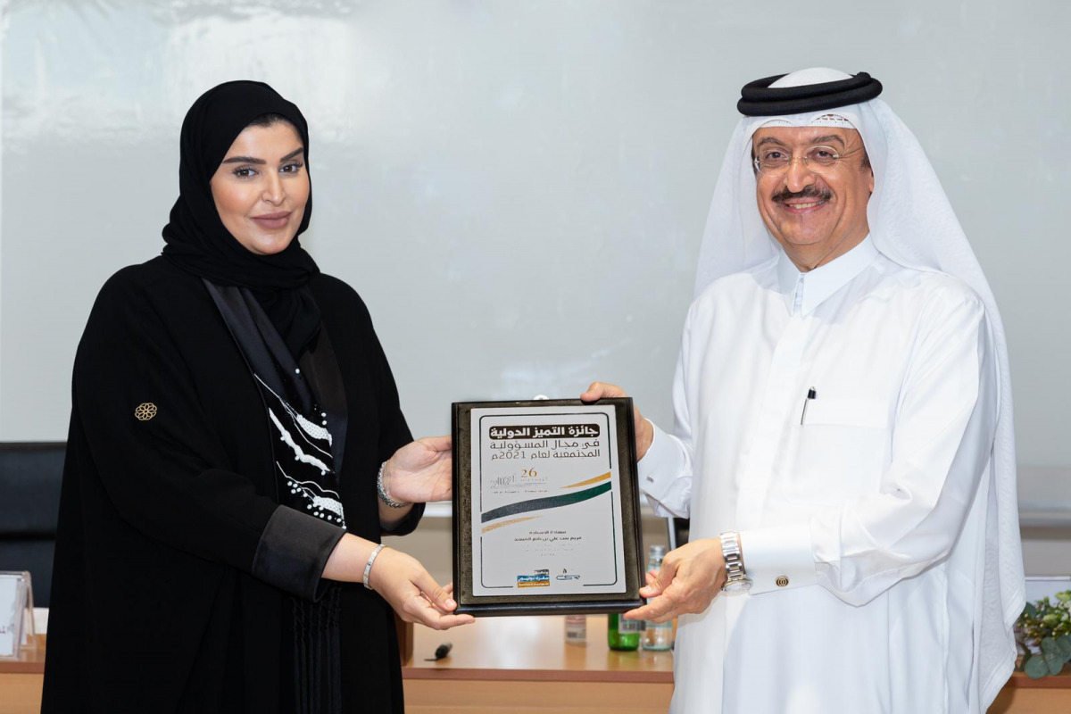International Ambassador for Social Responsibility Dr. Mohamed bin Saif Al Kuwari presenting the International Social Responsibility Excellence Award to Executive Director of Administration and Finance Division at the Doha Institute Mariam bint Ali bin Na