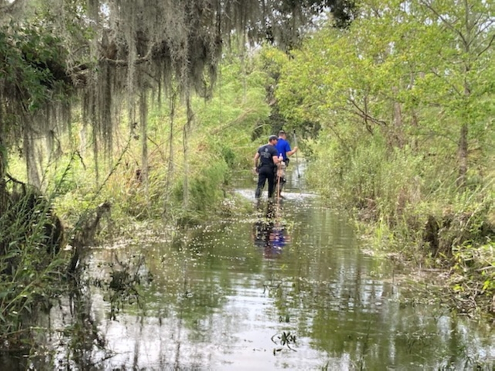 Sgt. Devin Coulon and Cpl. Chance Woods of the St. Tammany Parish Sheriff's Office searching for an alligator believed to have killed a man after Hurricane Ida in Slidell, Louisiana, in this handout picture obtained by Reuters on September 14, 2021. St. T