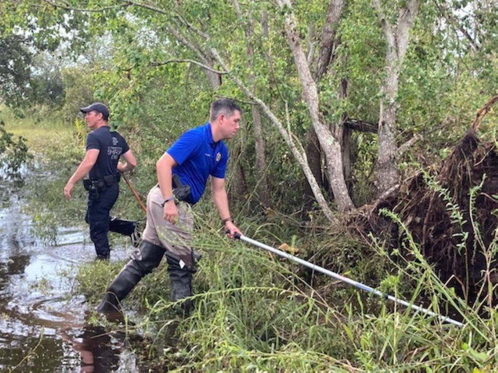 Sgt. Devin Coulon and Cpl. Chance Woods of the St. Tammany Parish Sheriff's Office searching for an Alligator believed to have killed a man after Hurricane Ida in Slidell, Louisiana, in this handout picture obtained by Reuters on September 14, 2021. St. T