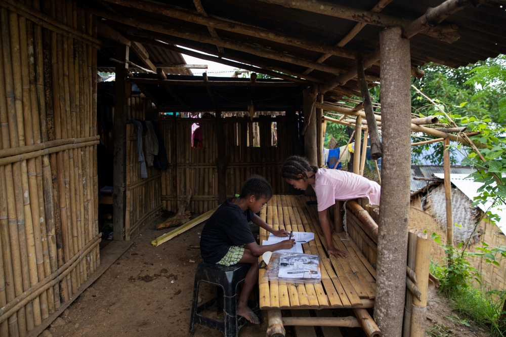 Seventh grade student Ryza Delos Santos, 10, works on her modules at home as her cousin observes, after a session at the makeshift rickshaw distance learning center for the Aeta community in Porac, Pampanga, Philippines, October 12, 2020. Picture taken Oc