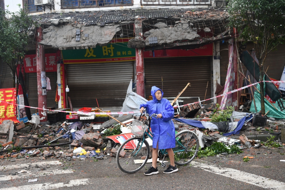 A person pushes a bicycle past damaged buildings, following an earthquake in Luzhou city of southwestern province of Sichuan, China September 16, 2021. cnsphoto/via REUTERS