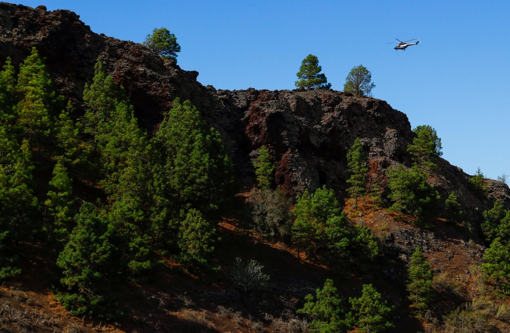 An emergency helicopter of the Government of the Canary Islands flies over an area where seismic movements are being felt in El Paso, on the Canary Island of La Palma, Spain, September 18, 2021. REUTERS/Borja Suarez