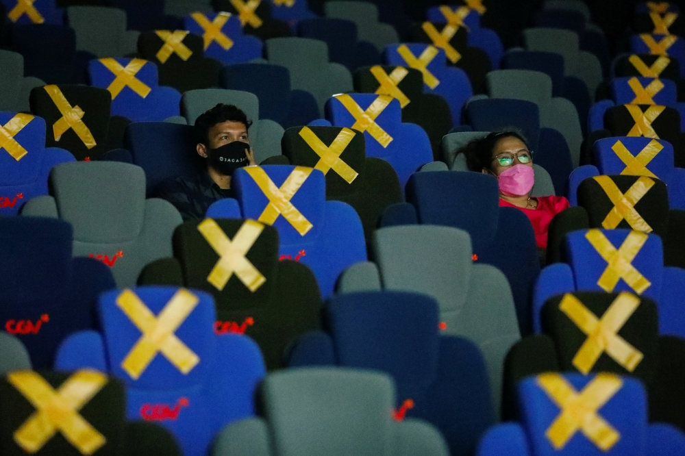 Visitors wearing protective masks watch a movie at a cinema as it is reopened after the ease of restrictions amid the coronavirus disease (COVID-19) pandemic in Jakarta, Indonesia, September 16, 2021. REUTERS/Willy Kurniawan/File Photo