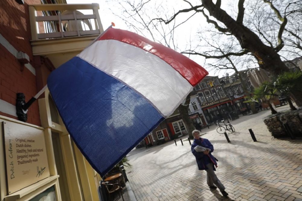A woman walks past a national flag, the day before a general election, in Delft, Netherlands, March 14, 2017. REUTERS/Yves Herma
