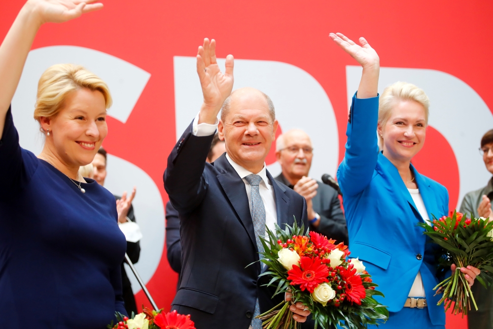 Social Democratic Party (SPD) leader and top candidate for chancellor Olaf Scholz, Mecklenburg-Western Pomerania state Prime Minister Manuela Schwesig and SPD member Franziska Giffey wave as they carry bouquets of flowers at their party leadership meeting