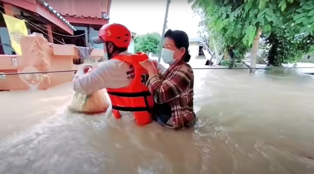 A rescuer uses a rope to carry a victim across flood waters in the Chaiyaphum province, Thailand, in this screen grab taken from a video from social media September 28, 2021. Picture taken September 28, 2021. Hook31 Thailand/via REUTERS