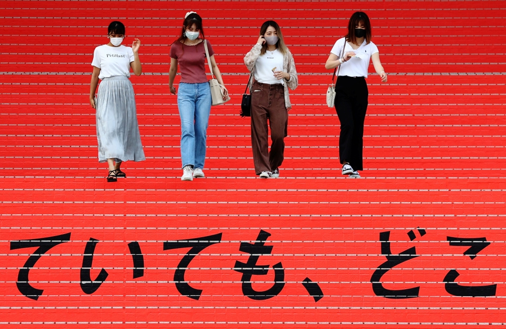 File photo: Women wearing protective masks, amid the coronavirus disease (Covid-19) outbreak, walk on a stair bearing a slogan cheering Japanese team during Tokyo 2020 Olympic Games in Tokyo, Japan, August 7, 2021. Reuters/Kim Kyung-Hoon/File Photo