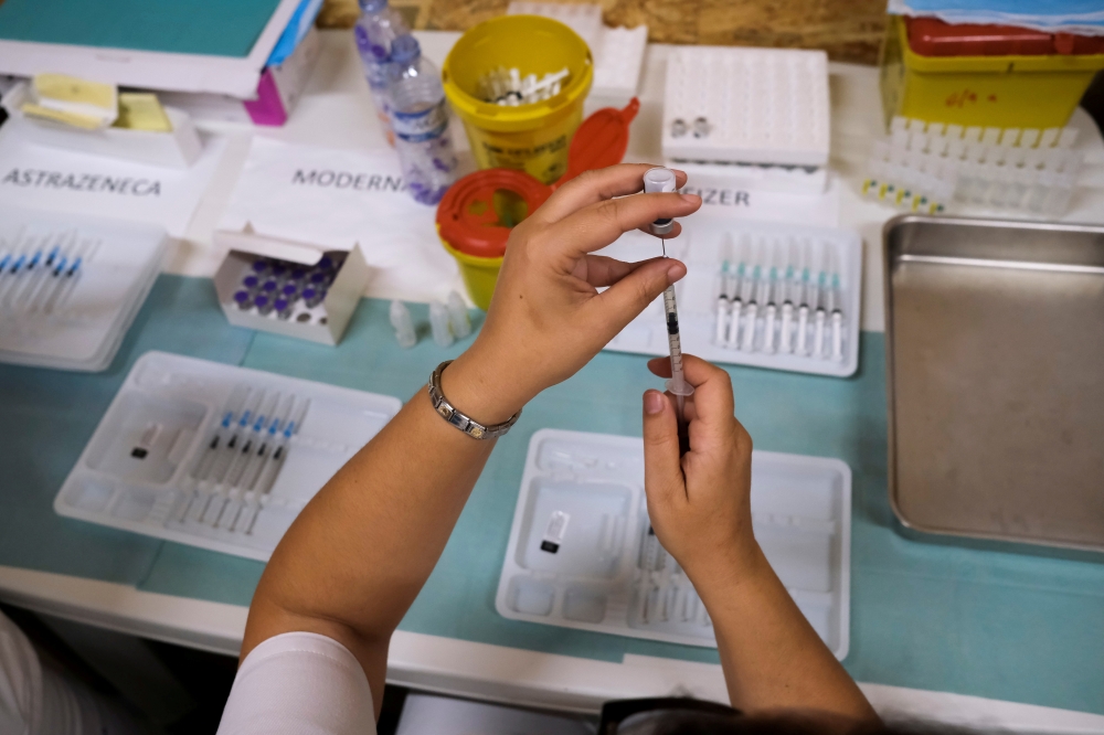 A healthcare worker prepares a dose of the Pfizer coronavirus disease (COVID-19) vaccine at a vaccination centre in Seixal, Portugal, September 11, 2021. REUTERS/Pedro Nunes/File Photo