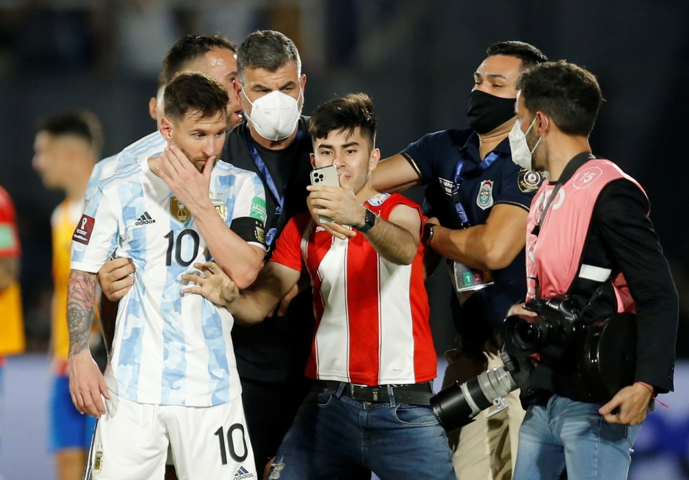 A pitch invader with Argentina's Lionel Messi after a match. (REUTERS/Cesar Olmedo)