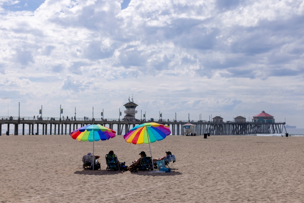 Beachgoers relax in the sand a long way from the water when authorities closed access after a major oil spill off the coast of California came ashore in Huntington Beach, California, U.S. October 4, 2021. Reuters/Mike Blake/File Photo