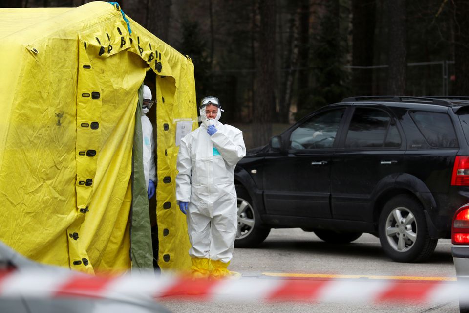 A health care worker wears protective suit as she waits for patients to be tested for coronavirus disease (COVID-19) next to a mobile laboratory in Riga, Latvia March 16, 2020. REUTERS/Ints Kalnins

