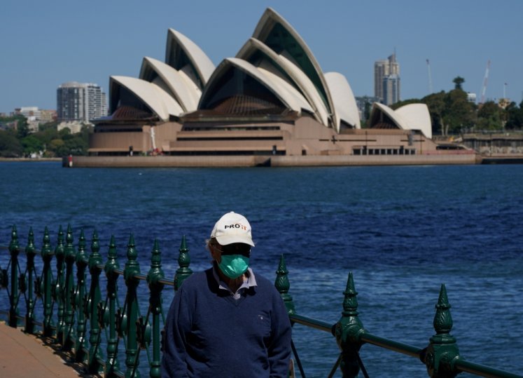 A person in protective face mask walks along the harbour waterfront across from the Sydney Opera House during a lockdown to curb the spread of coronavirus disease (COVID-19) outbreak in Sydney, Australia, October 6, 2021. REUTERS/Loren Elliott/File Photo