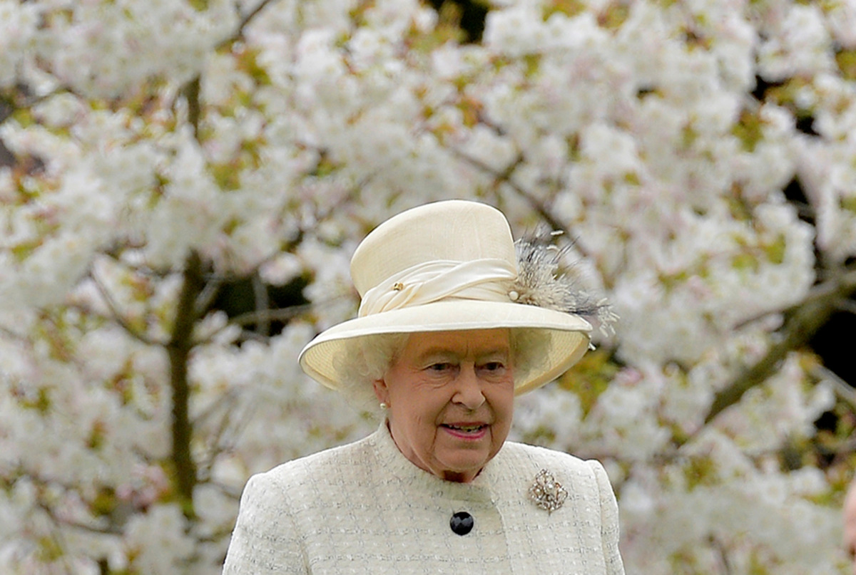 FILE PHOTO: Britain's Queen Elizabeth walks among spring blossom and flowers as she arrives to attend the unveiling of a statue in Windsor,southern England, March 31, 2014. REUTERS/Toby Melville/File Photo
