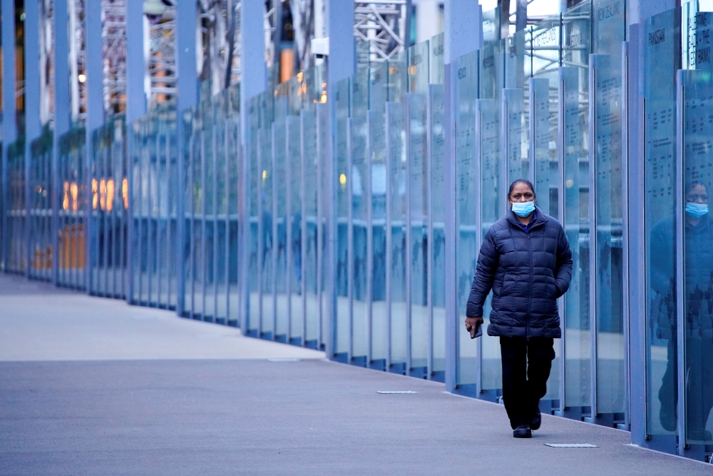 A woman wearing a protective face mask walks along a deserted city bridge during a lockdown as the state of Victoria looks to curb the spread of a COVID-19 outbreak in Melbourne, Australia, July 16, 2021. REUTERS/Sandra Sanders//File Photo/File Photo