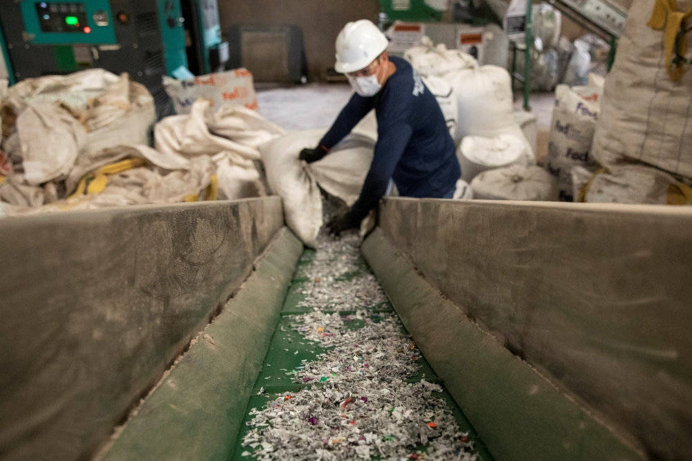 A worker loads shredded plastic to a machine to be molded into waterproof planks in the factory of social enterprise The Plastic Flamingo or The Plaf, in Muntinlupa, Philippines, October 18, 2021. The Plaf gathers plastics from restaurants, companies, and