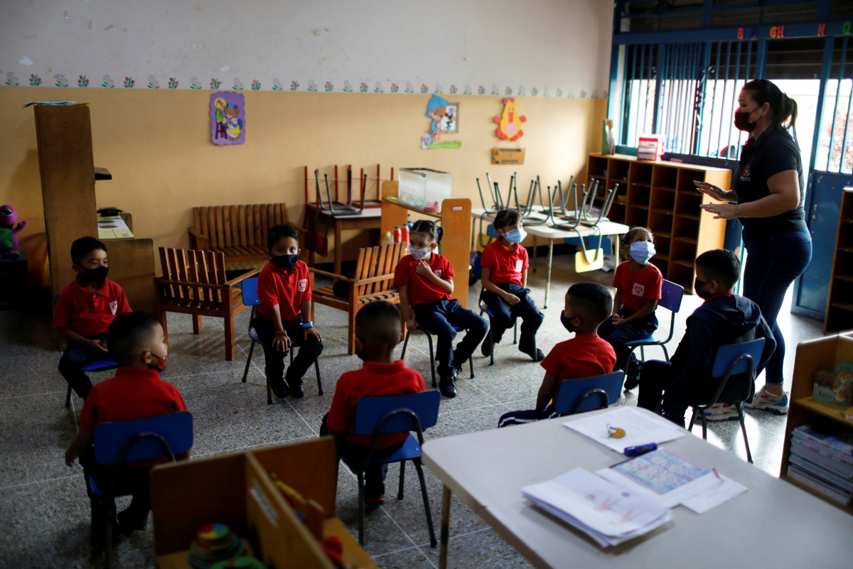 A teacher talks to children in the classroom about bio-safety rules, on the first day back to in-person instruction after it was suspended due to the coronavirus disease (COVID-19), in Caracas, Venezuela October 25, 2021. REUTERS/Leonardo Fernandez Vilori