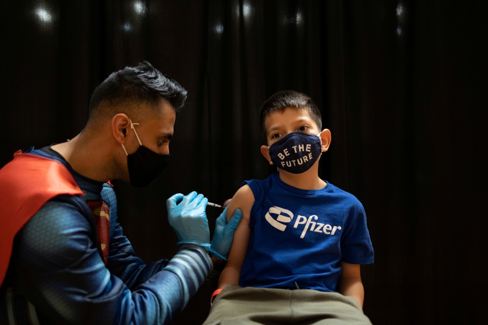 Dr. Mayank Amin administers the Pfizer-BioNTech coronavirus disease (COVID-19) vaccine to Evan Schuster, 7, in Collegeville, Pennsylvania, U.S., November 6, 2021. (REUTERS/Hannah Beier )