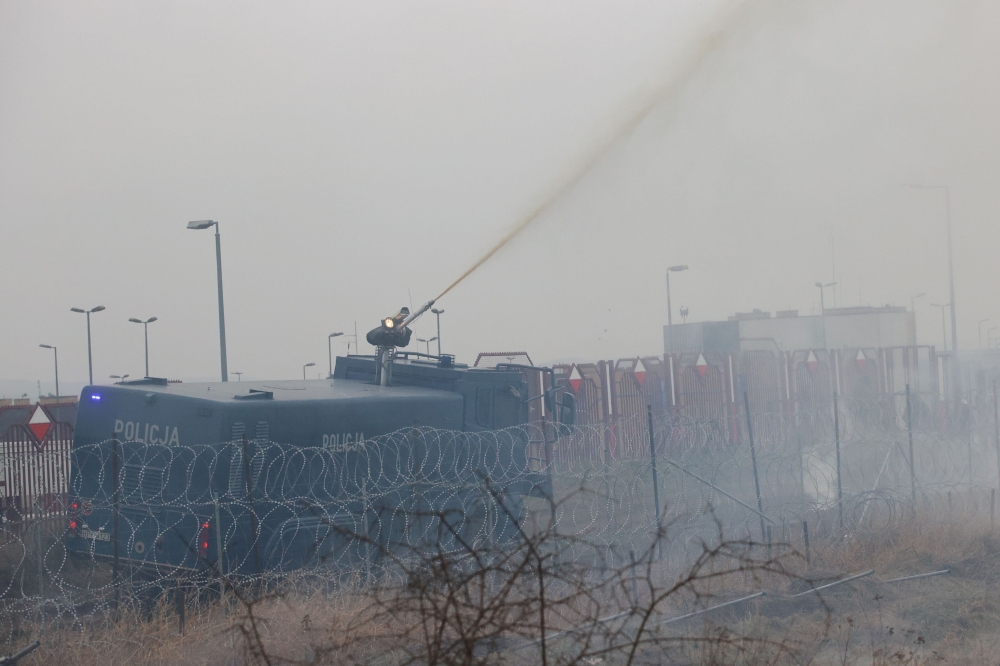 Polish law enforcement officers use a water cannon on migrants at Bruzgi - Kuznica checkpoint in the Grodno region, Belarus November 16, 2021. Leonid Scheglov/BelTA/Handout via Reuters 